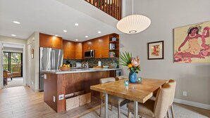 Una cocina moderna con armarios de madera, electrodomésticos de acero inoxidable y un comedor con mesa y sillas de madera.