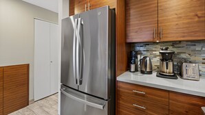 Una cocina moderna con electrodomésticos de acero inoxidable, armarios de madera y salpicadero de azulejos.