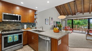 Una cocina moderna con armarios de madera, un microondas de acero inoxidable y un lavavajillas.