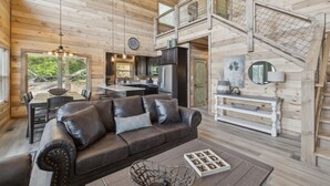 A spacious living area with a leather sofa, dining table, and kitchen in a wooden cabin.