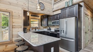 A modern kitchen with granite countertops, stainless steel appliances, and wooden accents.