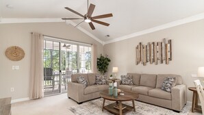 A spacious living room with a large sofa, a coffee table, and a ceiling fan. - River Crossing #1134 2 Bedroom Condo (North Myrtle Beach)