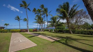 A shuffleboard court with a clear view of the ocean and palm trees in the background. - Menehune Shores 227 2 Bedroom Condo (Kihei)