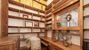 Interior de madera con estantes, un escritorio y un ventanal decorado con un adorno floral.