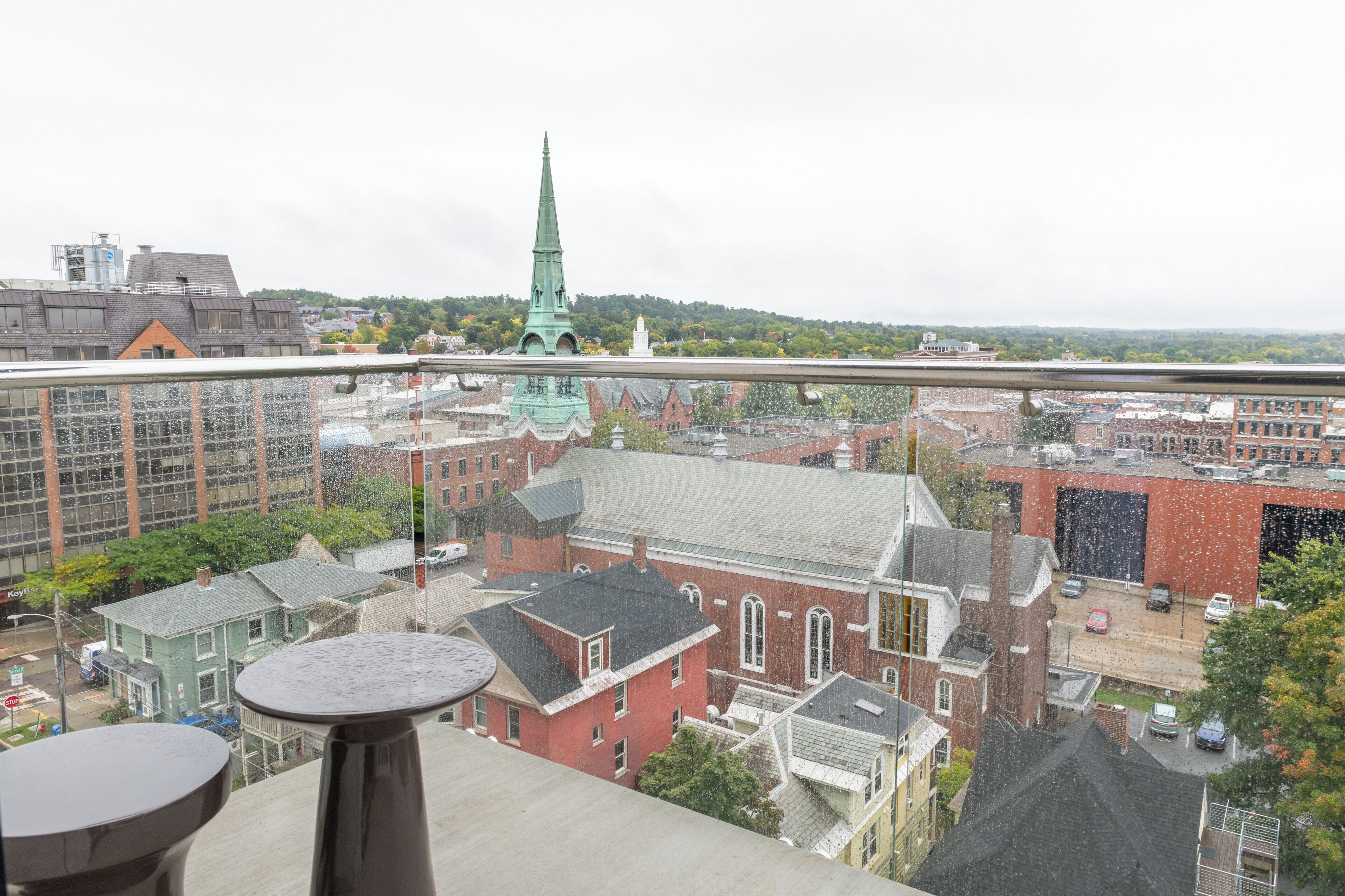 A high-rise building with a view of a cityscape, including a church spire.
