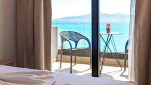A hotel room with a bed, a balcony with a view of the sea, and a table with a potted plant. - Alpaso Hotel (Sarande)