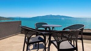 A terrace with wicker furniture and a view of the sea and mountains. - Alpaso Hotel (Sarande)