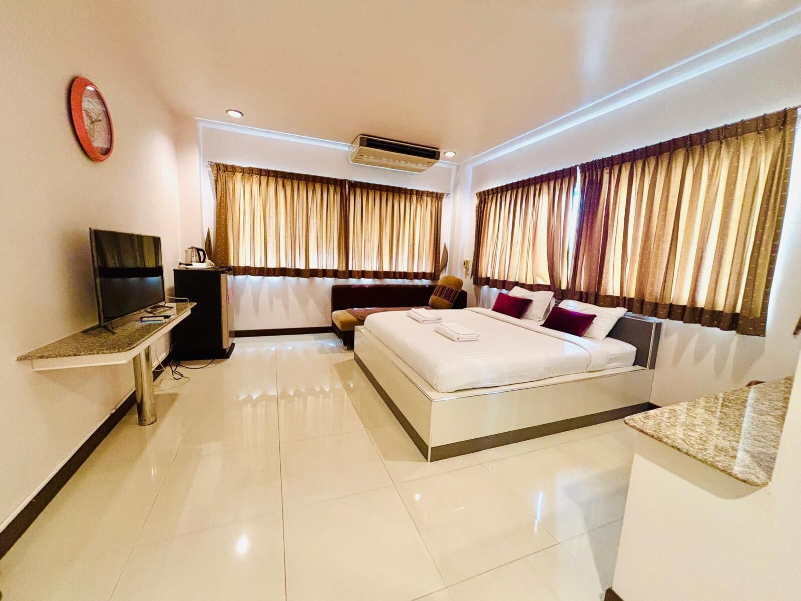A hotel room with a bed, a desk with a TV, and curtains.
