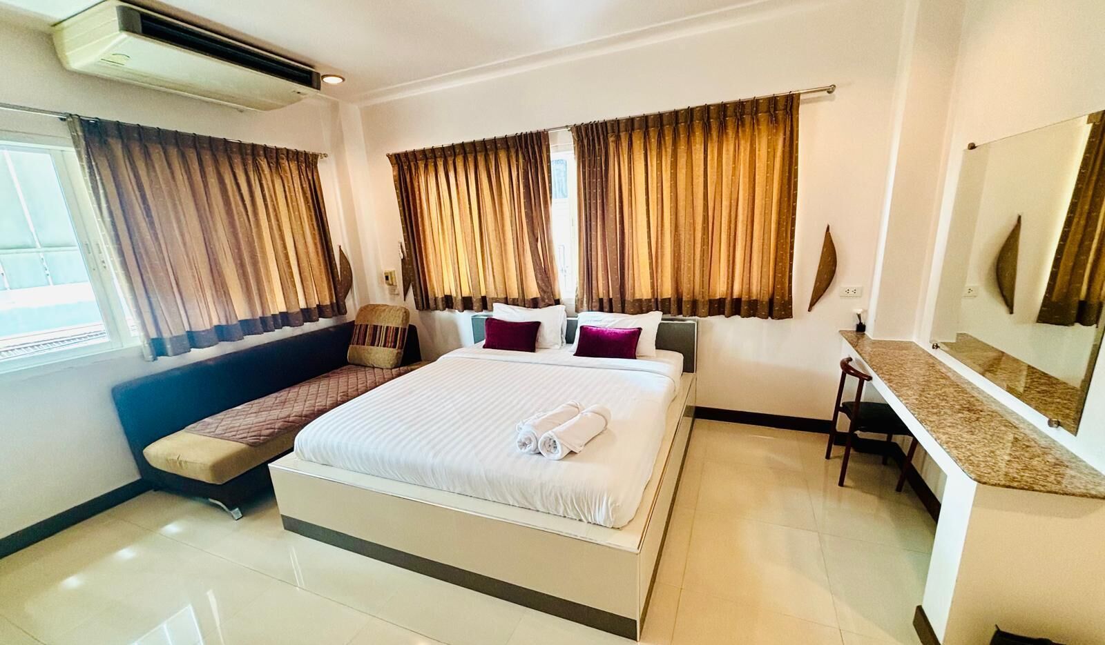 Una habitación de hotel con una cama, un escritorio, una silla y un banco.