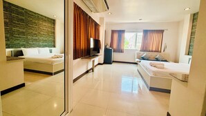 Una habitación de hotel con cama, sofá, televisor y espejo.