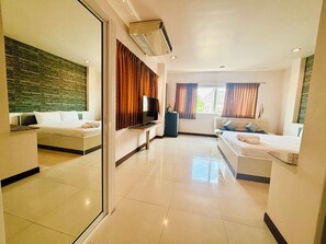 Une chambre d’hôtel avec un lit, un canapé, une télévision et un miroir.