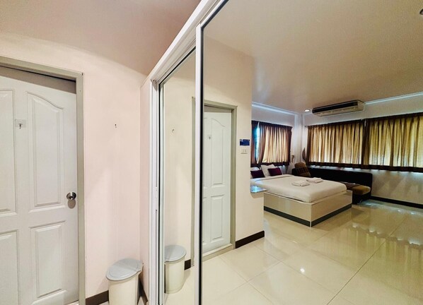 Une chambre d’hôtel dotée d’un grand lit, d’un coin salon avec un canapé et des fauteuils, d’une petite table et d’un miroir.