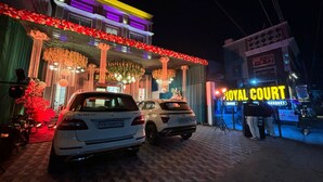 Un edificio con un letrero que dice "ROYAL COURT" y dos coches estacionados en la entrada.