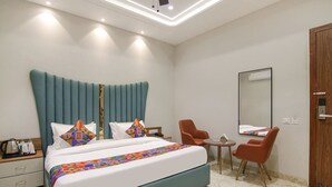 Una habitación de hotel moderna con una cama grande, dos sillas, una mesita y un espejo.