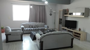 Una sala de estar moderna con un sofá, una mesa de centro, un televisor y una estantería.