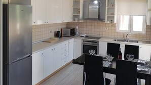 Una cocina moderna con armarios blancos, un refrigerador de acero inoxidable, un microondas y un comedor con mesa y sillas.