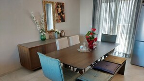A dining area with a wooden table, blue cushioned chairs, and a bench. There is a mirror on the wall and a painting above the table. - Rethymno Suburb Maisonette (Rethymno)