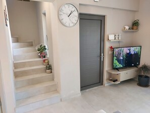 Stylish living space with a staircase, flat-screen TV, and potted plants.
