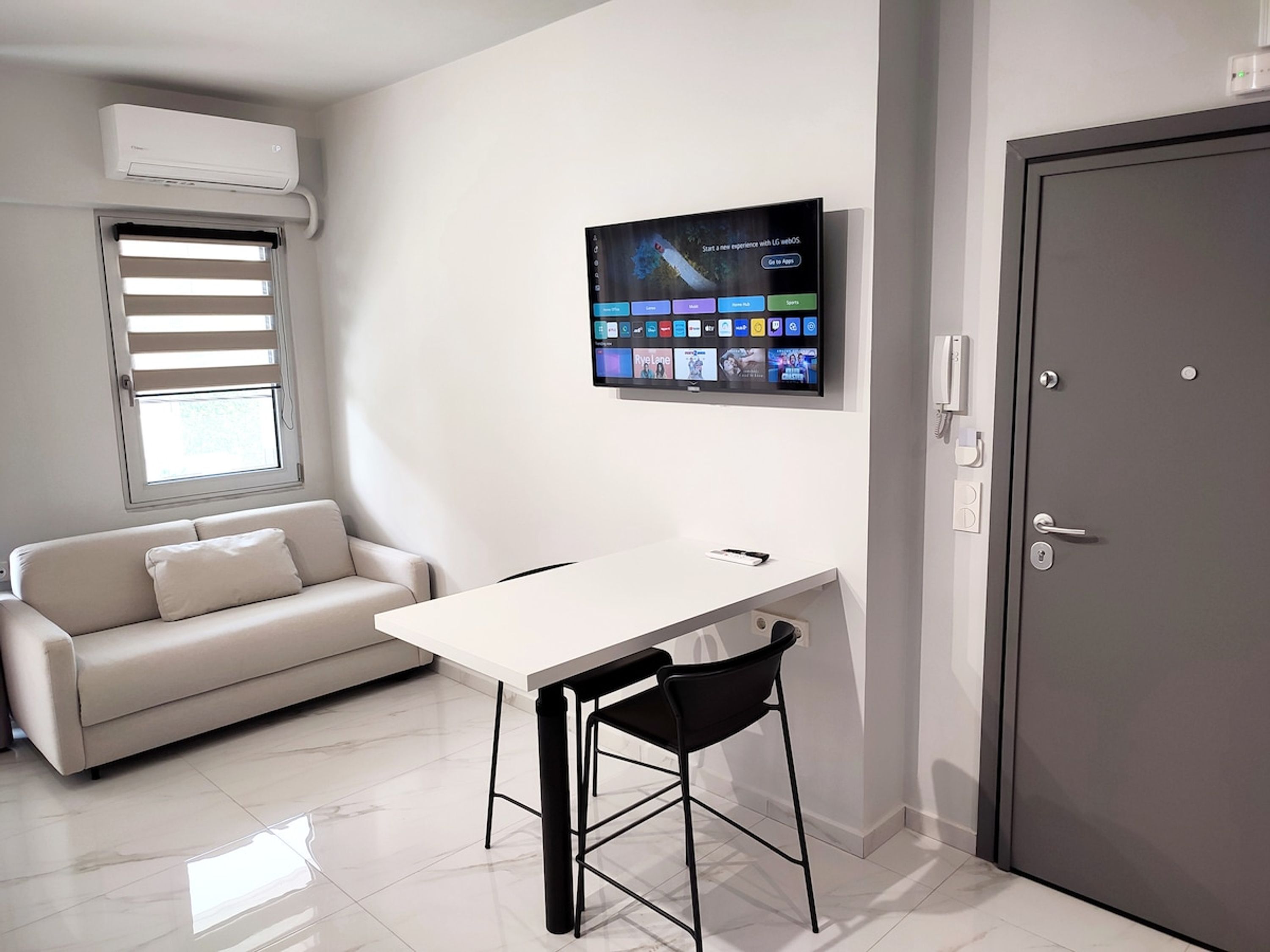 Une pièce moderne avec une table blanche, une chaise noire et une porte grise.