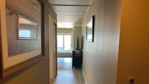 Un pasillo con una cama, un aparador y un cuadro en la pared.