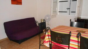 A small dining area with a table and chairs, a purple sofa, and a window with blinds. - 8 pers, 200m from the sea, garden, ground floor, closed private parking, independent entrance (Marseillan)