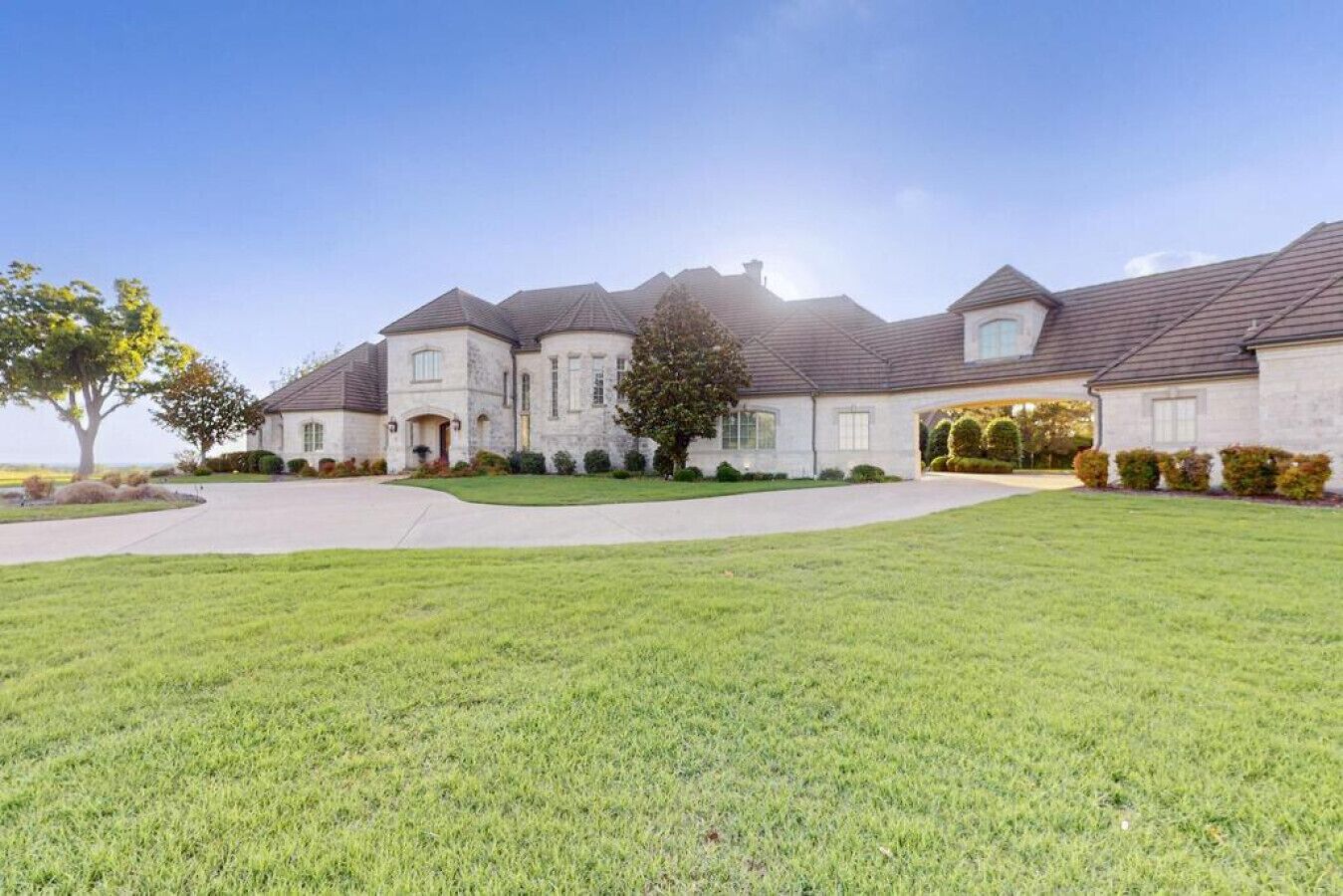 A large, two-story house with a well-maintained lawn and a driveway leading to the entrance.