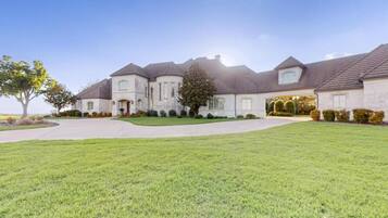 A large, two-story house with a well-maintained lawn and a driveway leading to the entrance.