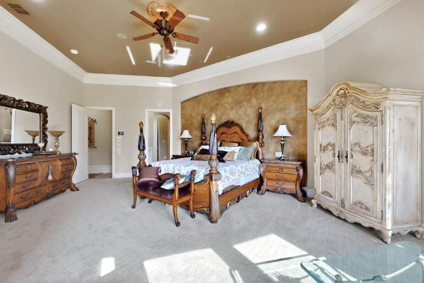 A spacious bedroom with a large bed, a ceiling fan, and a classic wardrobe.