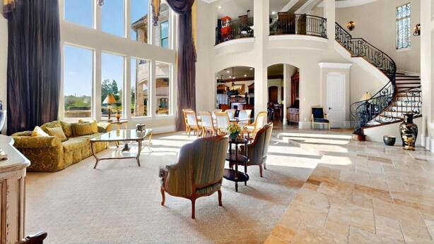 Un vaste espace de vie comprenant un grand canapé, une table à manger et des chaises, un escalier et une vue sur l’extérieur.