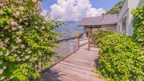 A wooden deck leading to a house with a view of mountains.