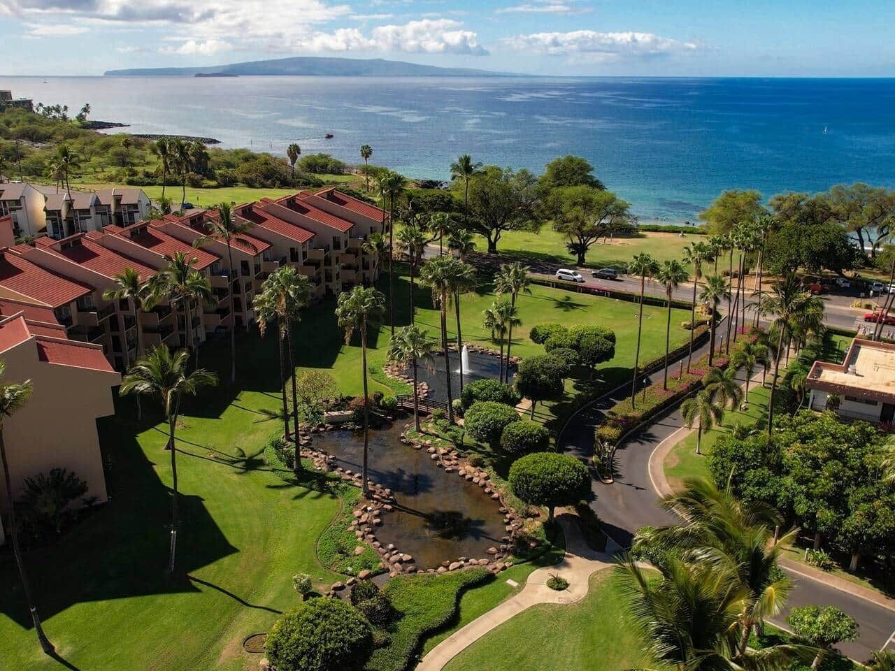 Een resort met meerdere gebouwen, een fontein in het midden en uitzicht op de oceaan.