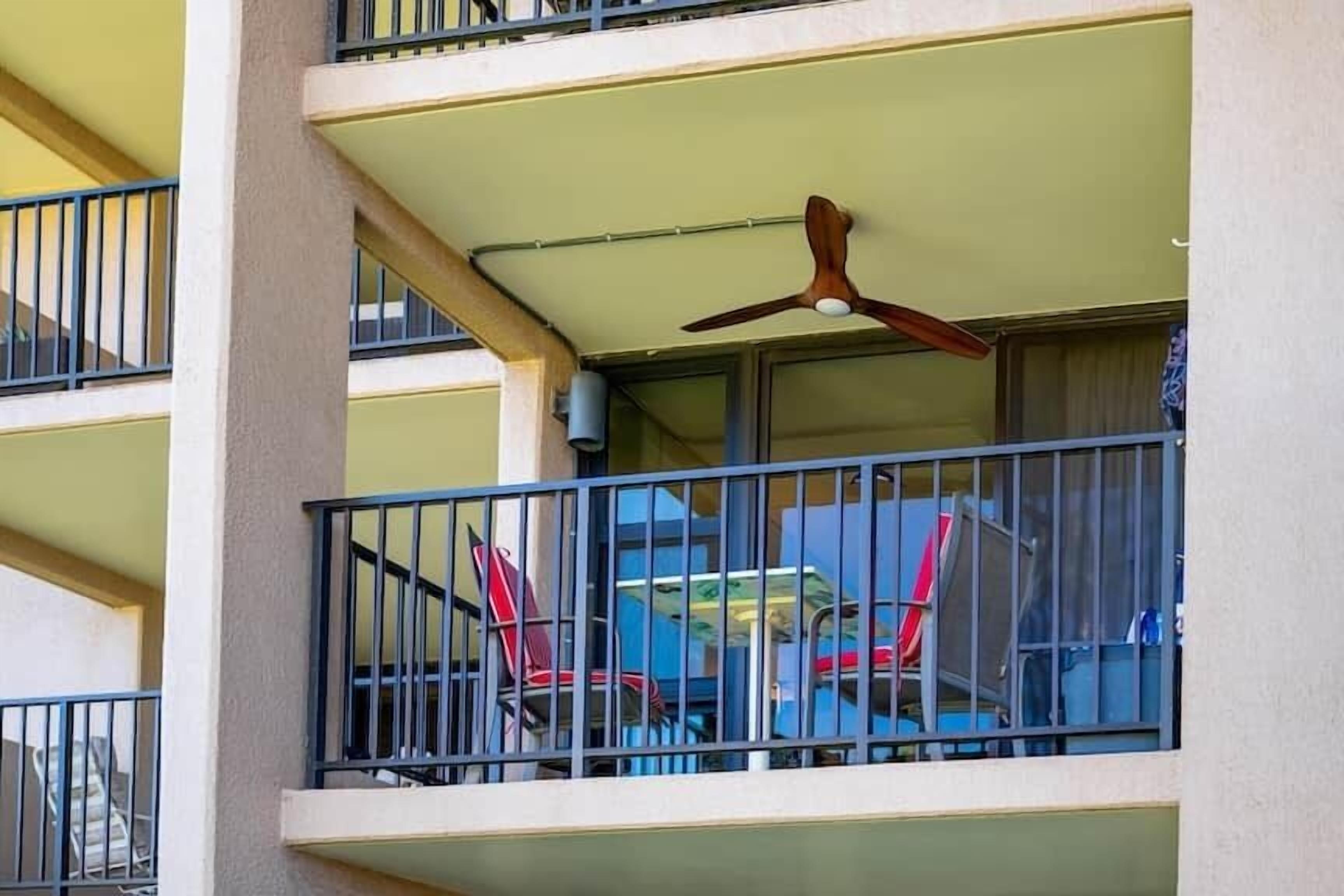 A multi-story building with balconies, a ceiling fan, and outdoor furniture.