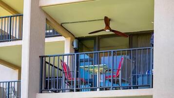 A multi-story building with balconies, a ceiling fan, and outdoor furniture.