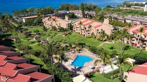 A resort with multiple buildings, a central swimming pool, and surrounding greenery.
