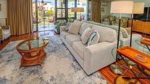 A living room with a sofa, a glass coffee table, and a lamp.