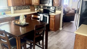 A modern kitchen with wooden cabinets, a stainless steel stove, and a dining area with a wooden table and chairs.