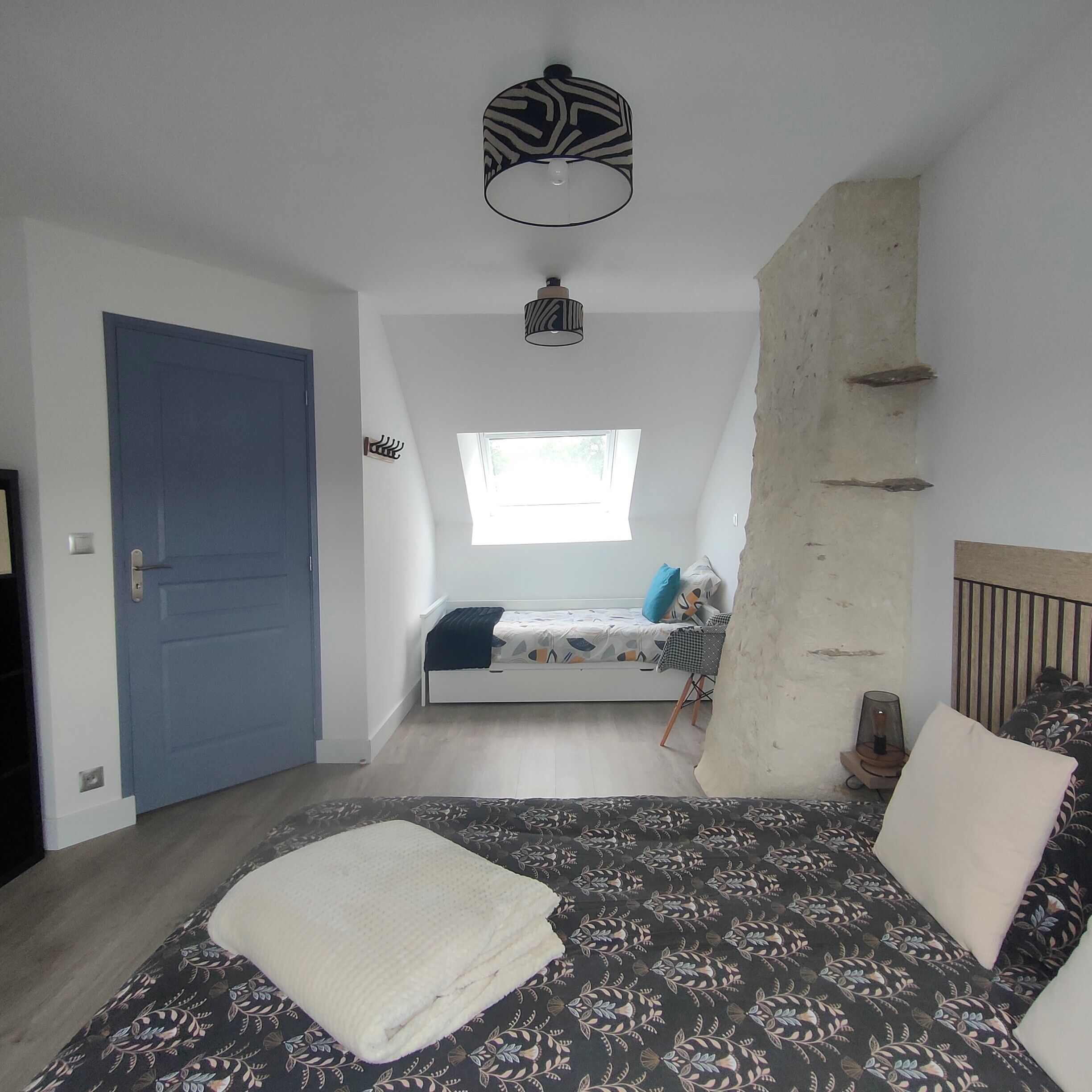 Une chambre à coucher avec un lit, une fenêtre, une porte et un luminaire au plafond.