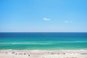 A beach with clear blue water and a sandy shore.