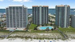 Un hotel frente a la playa con tres edificios de gran altura, una piscina central y una zona de playa.