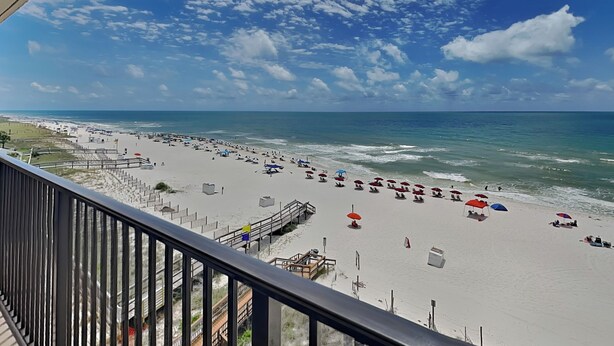 A beach with umbrellas and people, a pier, and a clear sky. - Ocean Breeze East 602, 2BD/2BA, Gulf-Front, Pool + Private Beach Access (Perdido Key)