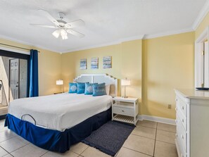 A bedroom with a bed, nightstands, a dresser, a ceiling fan, and artwork on the wall.