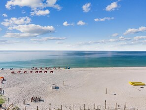A beach with umbrellas and sun loungers, a lifeguard stand, and a clear view of the ocean. - Ocean Breeze East 602, 2BD/2BA, Gulf-Front, Pool + Private Beach Access (Perdido Key)