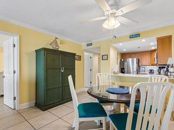 A dining area with a round table, chairs, and a ceiling fan.