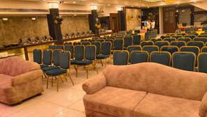 A conference room with rows of chairs, a stage, and a bar area. - HOTEL KRISHNA PARADISE (Agra)