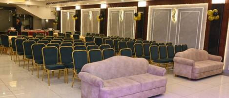 A conference room with rows of chairs, a stage, and two sofas.