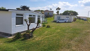 A mobile home with a small attached garage and a car parked in front.