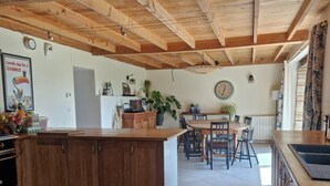 A spacious kitchen with wooden beams, a central island, and a dining area with chairs and a table. - Mas Crudel - Character house in the South of France (Parisot)