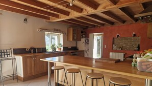A kitchen with wooden beams, a large island with stools, and a view to the outside. - Mas Crudel - Character house in the South of France (Parisot)