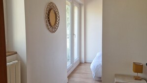 A bedroom with a wooden floor, a bedside table with a lamp, a bed, and a window with a view of greenery. - Mas Crudel - Character house in the South of France (Parisot)