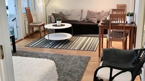 A modern living room with a sofa, two chairs, a small table, and a lamp. - Kotimaailma KotikaksioMallask saunalla (Lahti)